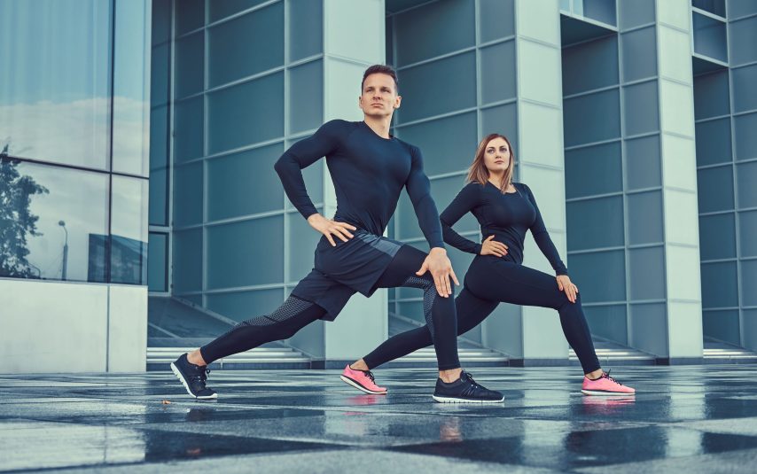young-fitness-couple-sportswear-doing-lunges-modern-city-against-skyscraper-healthy-lifestyle-concept
